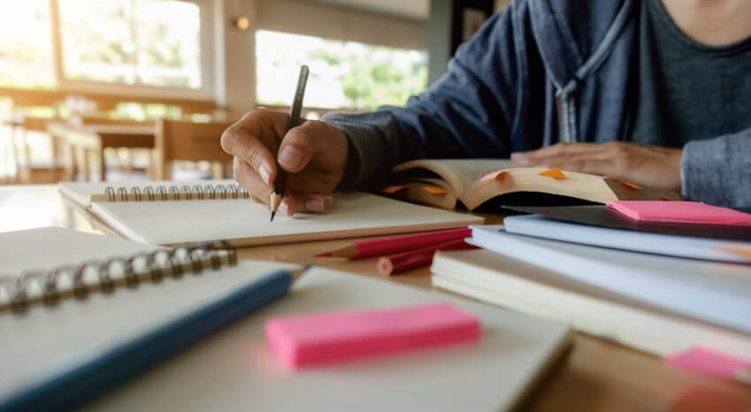 A student diligently writes in a notebook, focused on completing their homework assignment.