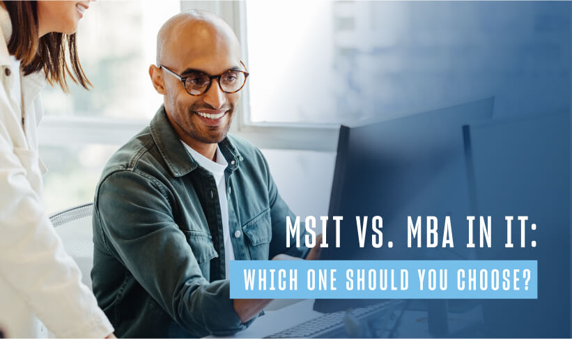 bald man with glasses smiles and points at a computer screen as a coworker stands beside him to review the screen