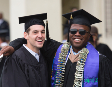 Two men in graduation cap and gowns smiling