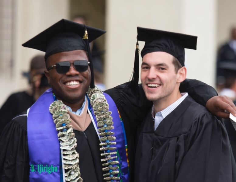 Two college graduates smiling in their cap and gowns