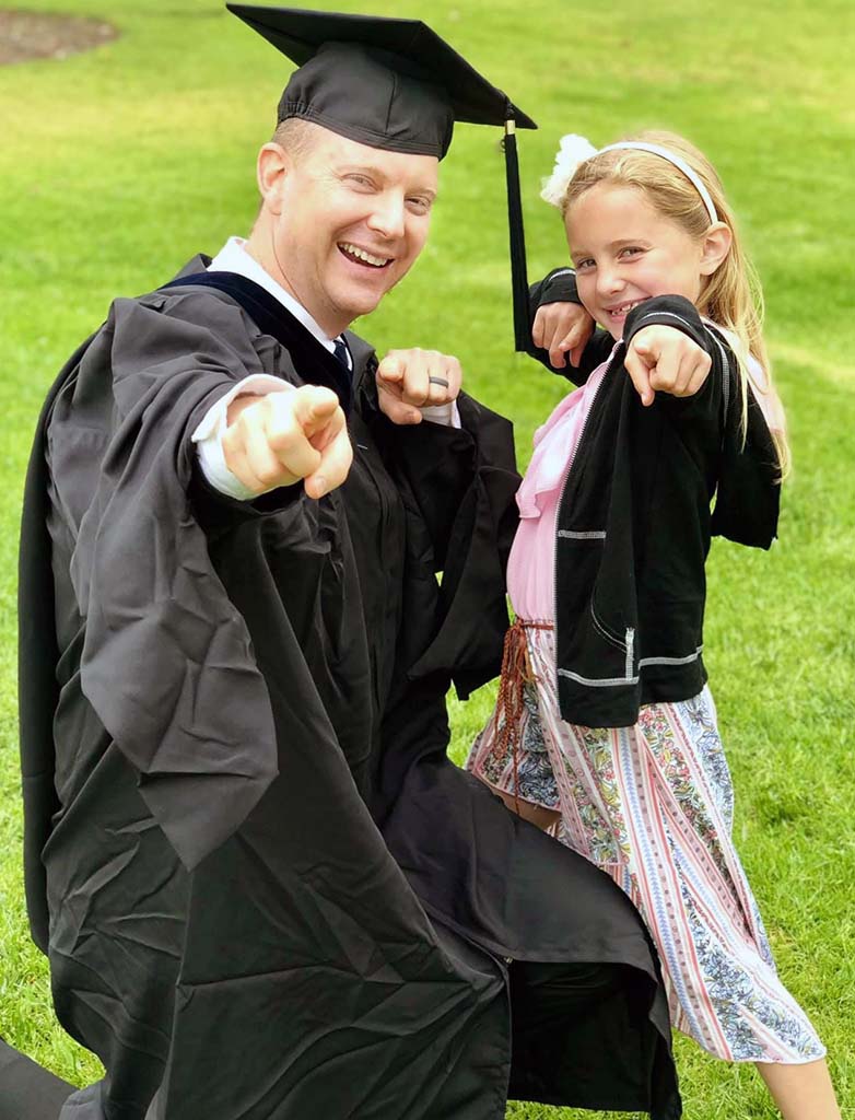 father in his master's graduation cap a gown smiling with his daughter