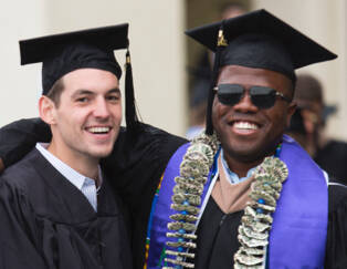 Two men in graduation cap and gowns smiling