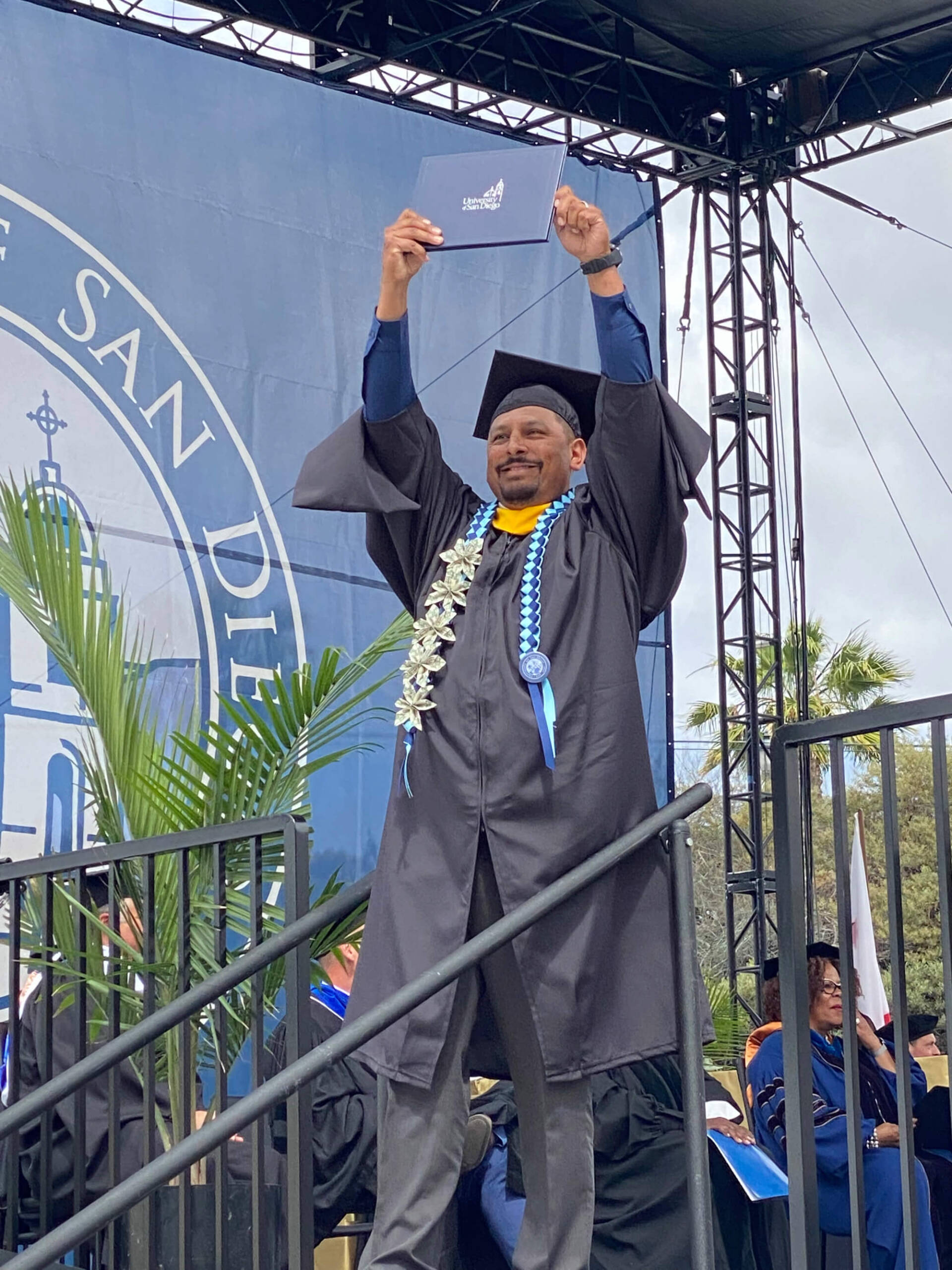 a student holds his degree on stage during a graduation ceremony