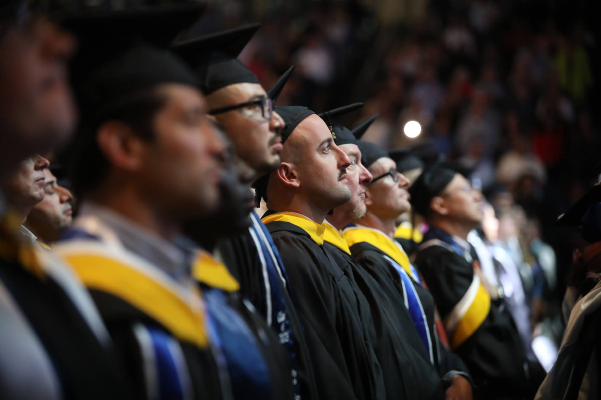 students look at the stage from the audience during a graduation ceremony