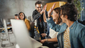 Lecturer Helps Scholar with Project, Advising on Their Work. Teacher Giving High Five to Diverse Multiethnic Group of Female and Male Students in College Room, Teaching Software Engineering.