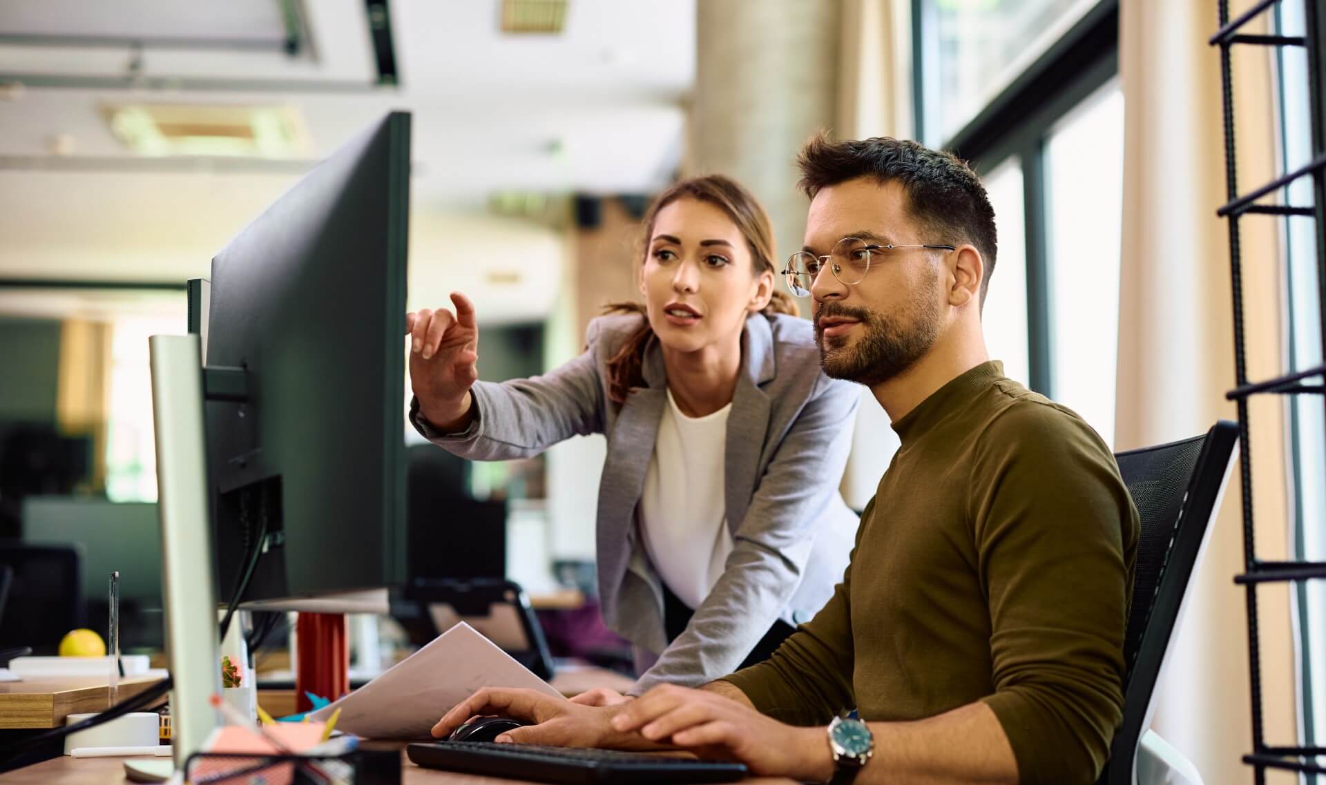 man and woman looking at computer screen at work