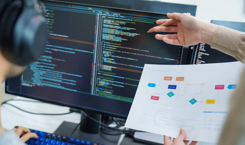 A man pointing at a computer screen showing lines of code.