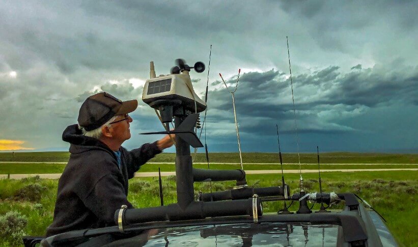 Man checking weather conditions with station on vehicle.