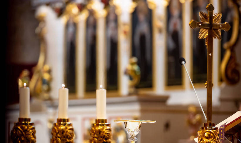 A gold altar adorned with lit candles and a shining gold cross, creating a serene and sacred atmosphere.