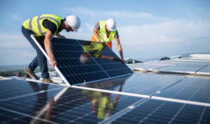 Two engineers installing solar panels on roof.