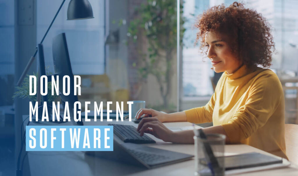 woman with curly brown hair wearing a yellow turtleneck sits by an office window at a desk working on a desktop computer. Text on image reads "donor management software"