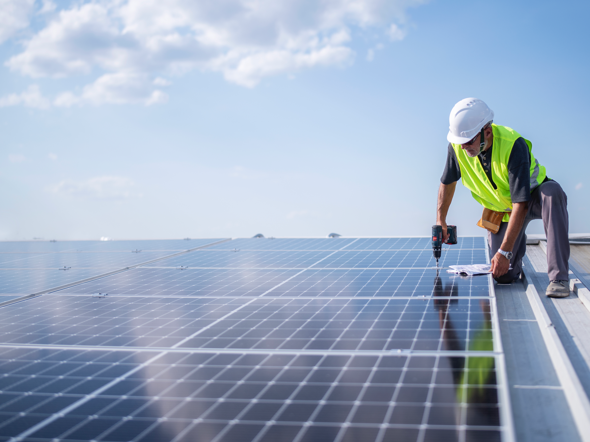 Man on roof installing solar panel system.