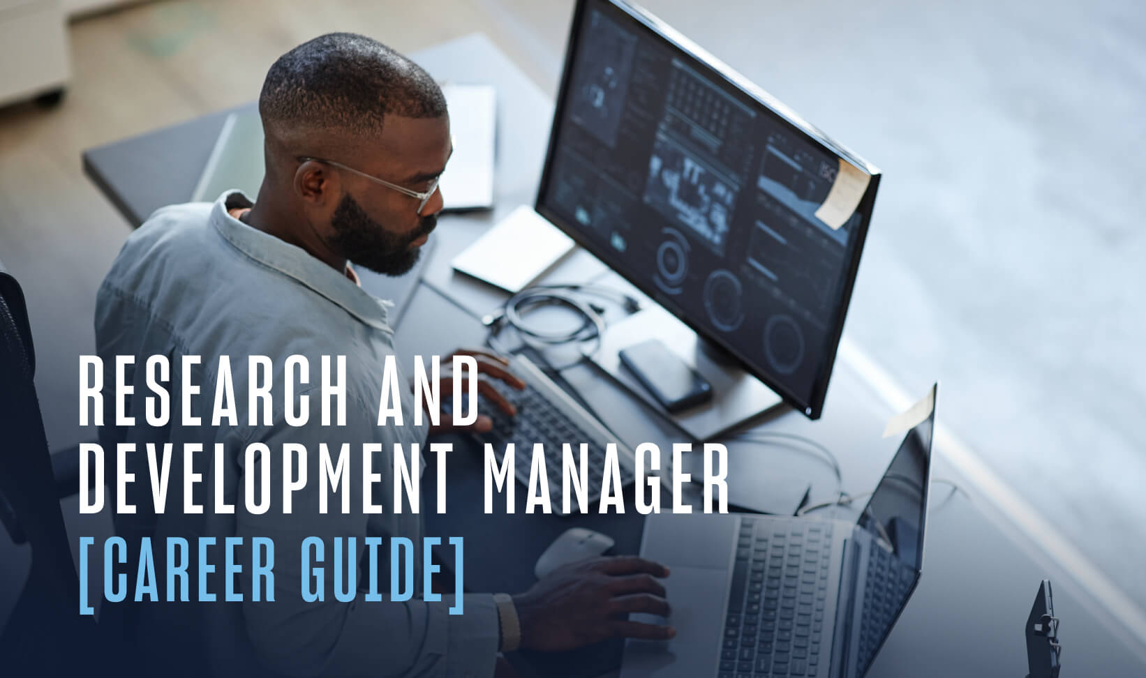 person sitting at desk looking at laptop and monitor