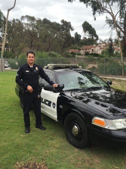 ryan opeka poses in front of a black and white cop car
