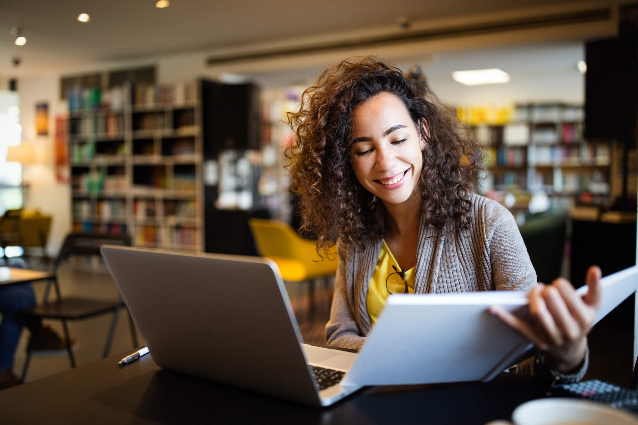 woman sitting at a table with books and laptop
