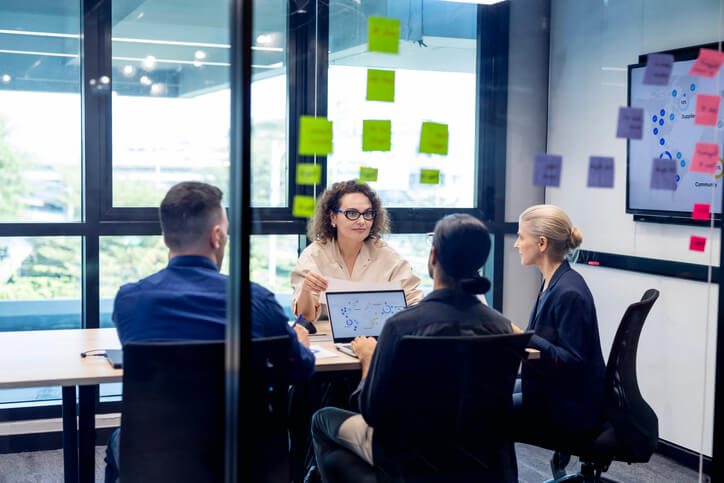 People sitting at a table in a conference room looking at data