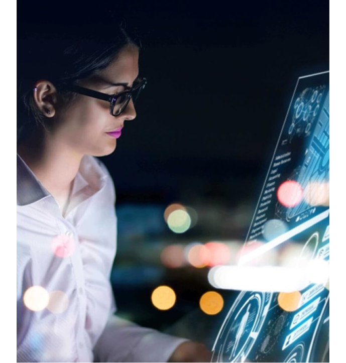 Woman wearing glasses interacts with a futuristic digital touchscreen interface displaying data and analytics.