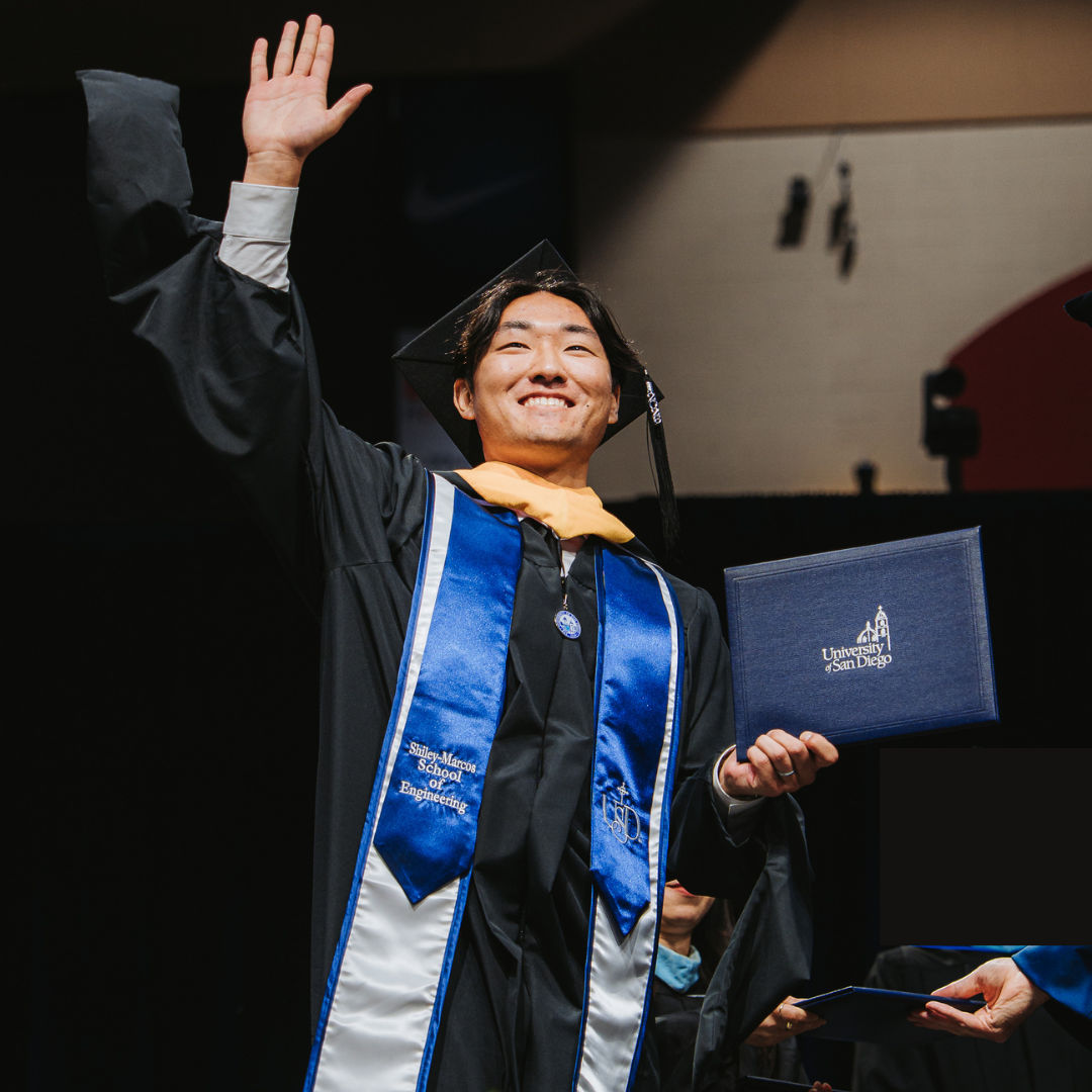 USD graduate waving at commencement