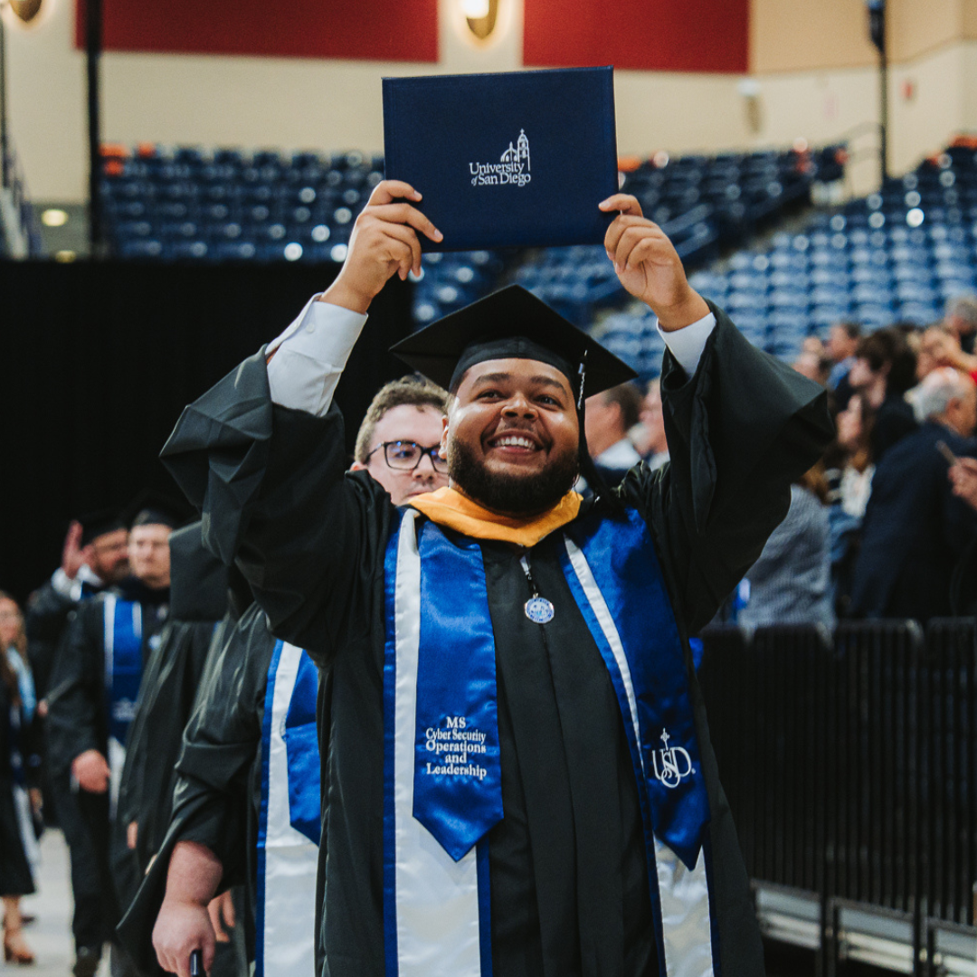 USD graduate holding degree over their head